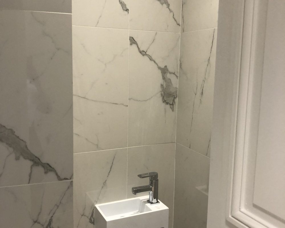 Toilettes avec lave-mains et carrelage effet marbre