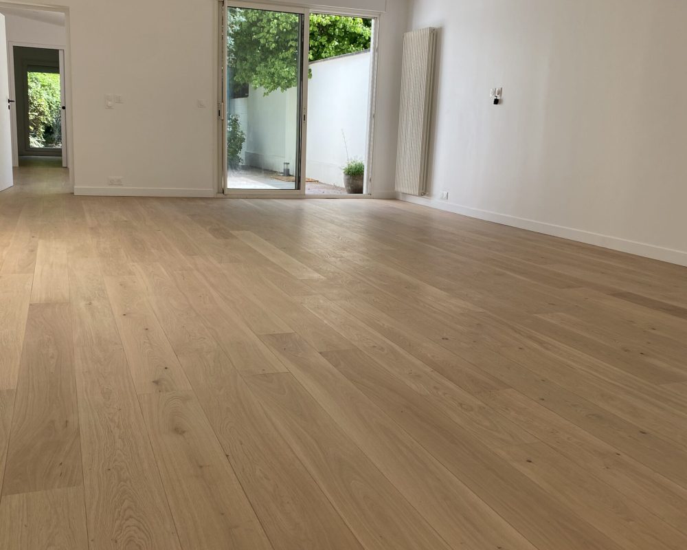 Salon lumineux avec parquet clair et accès terrasse