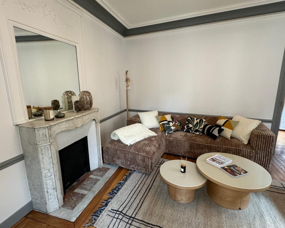 Salon cosy avec cheminée ancienne et canapé d’angle