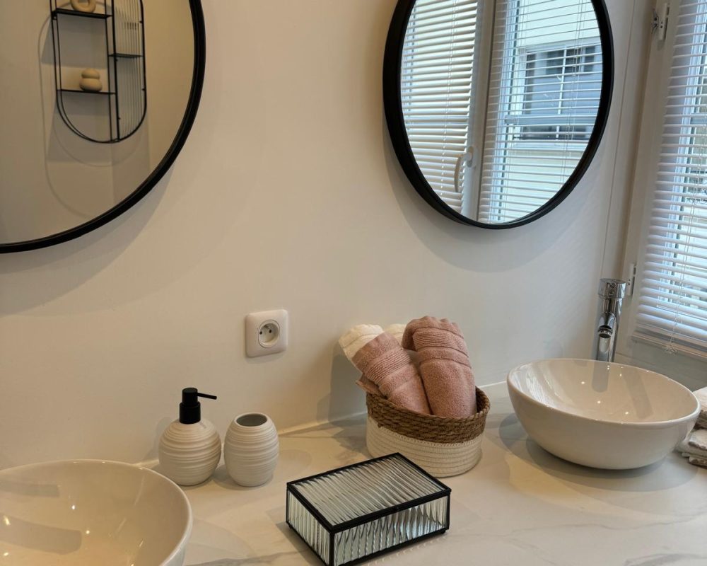 Salle de bains minimaliste avec vasques rondes et miroirs noirs